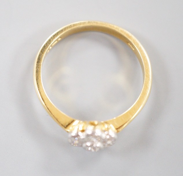 A modern 18ct gold and collet set seven stone diamond set flower head cluster ring, size O, gross weight 3.7 grams